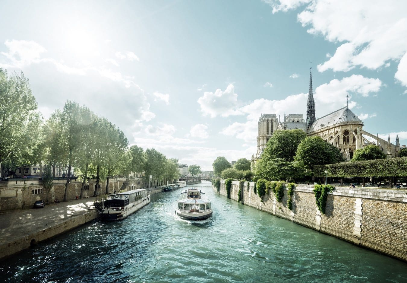 river cruise in paris gliding by notre dame cathedral in summer