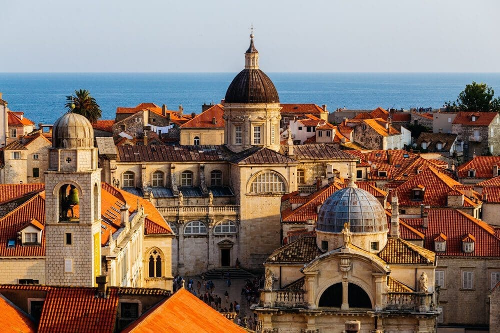 Domes and red-roofs over Dubrovnik's old town with the blue sea in the background.