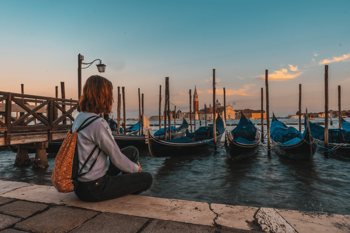 Woman sits by the water and gondolas in Venice